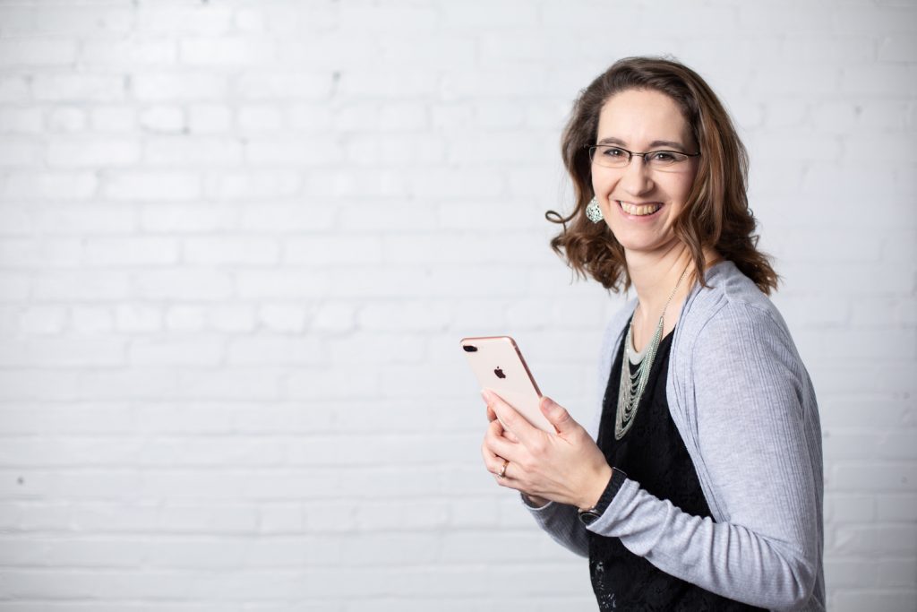 A blogger smiling while holding a phone